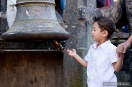 young boy ringing stone bell